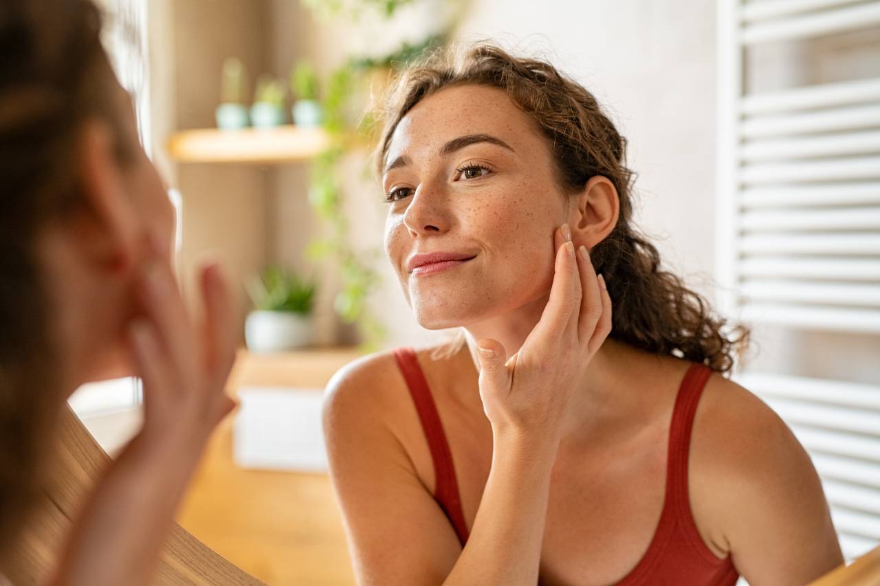 A woman examining her skin after an anti-aging facial treatment at Radiant Health in Sioux Falls